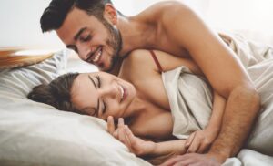 Happy couple in bed smiling due to improved sexual wellness treatments in Austin, TX